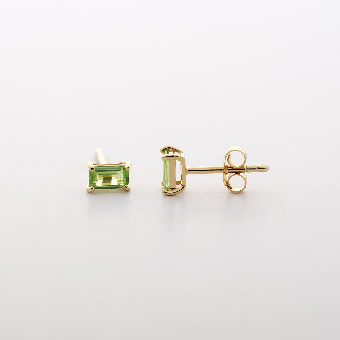 Nahaufnahme von zwei CHRIST 585er Gelbgold Ohrsteckern mit rechteckigen, hellgrünen Peridot Farbsteinen.