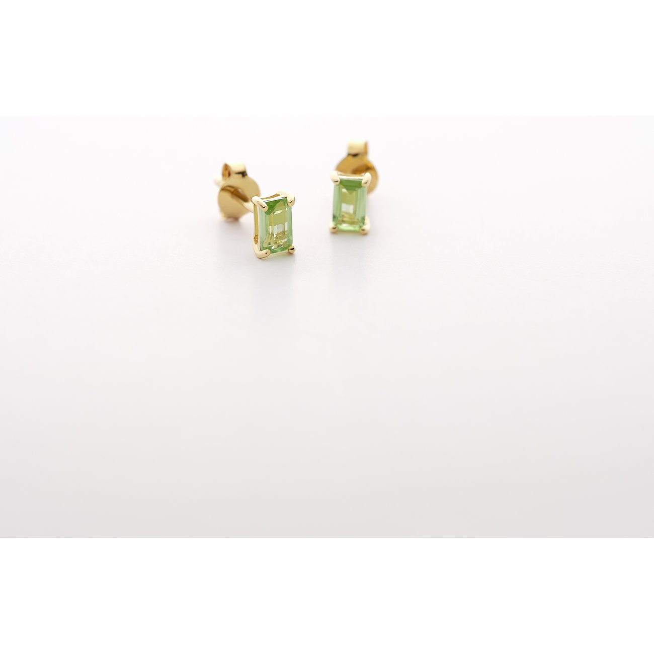 CHRIST Ohrschmuck aus 585er Gelbgold mit facettierten, rechteckigen Peridot-Edelsteinen, seitlich von oben gesehen.