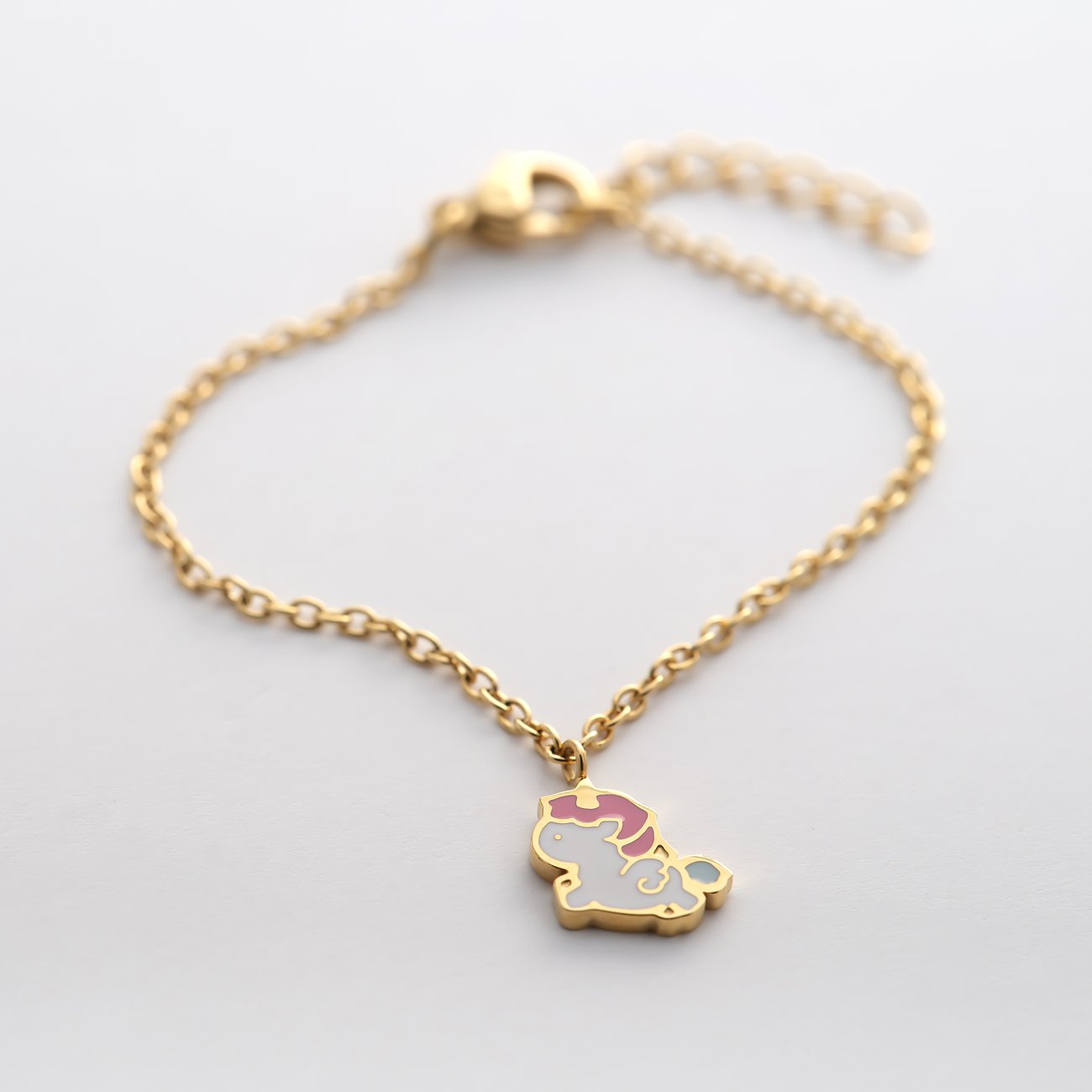 Bracelet FAVS Little Friends en acier inoxydable doré avec un pendentif licorne en émail blanc et crinière rose.
