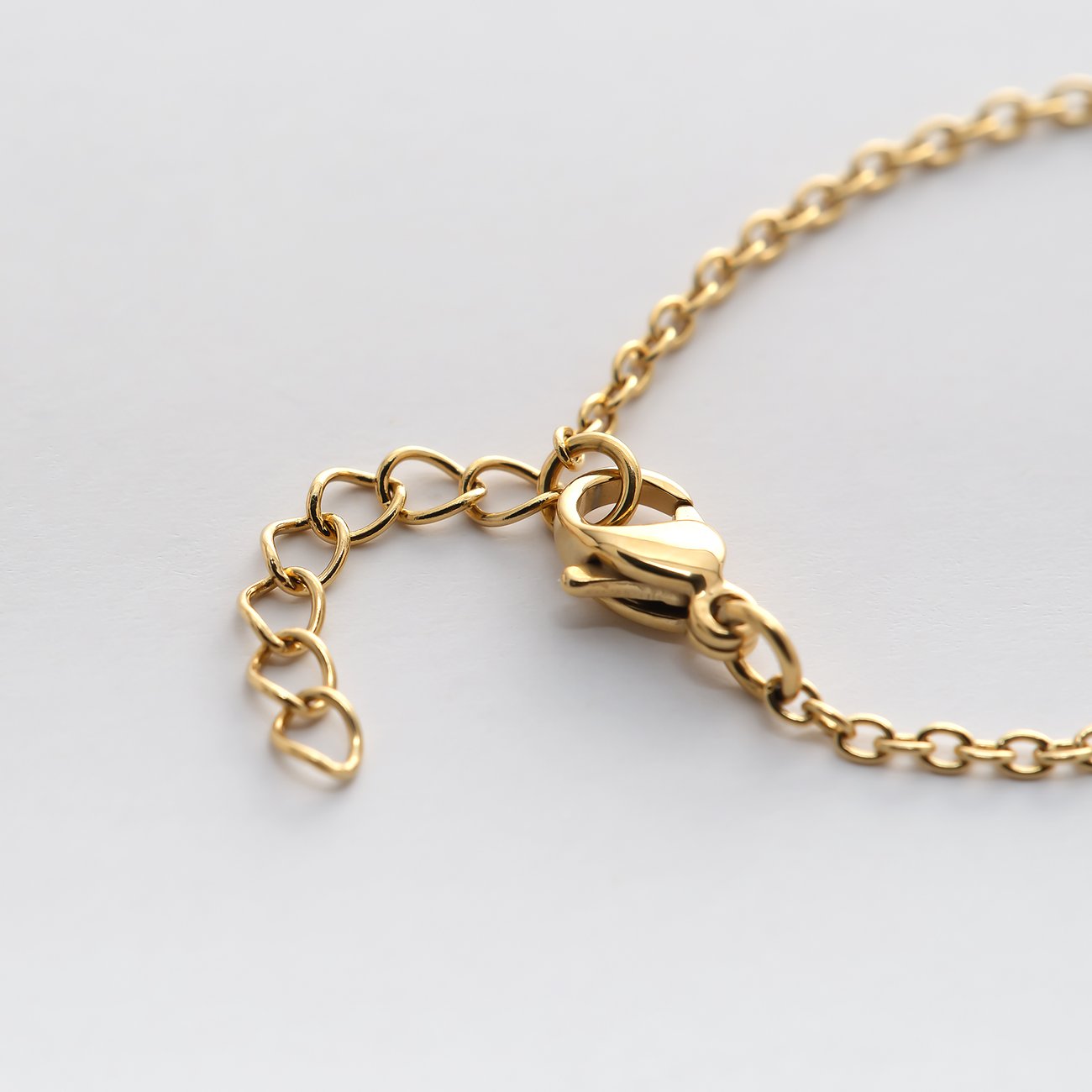 Gros plan sur le fermoir et la chaîne d'extension en acier inoxydable couleur or d'un bijou de bras FAVS Little Friends.