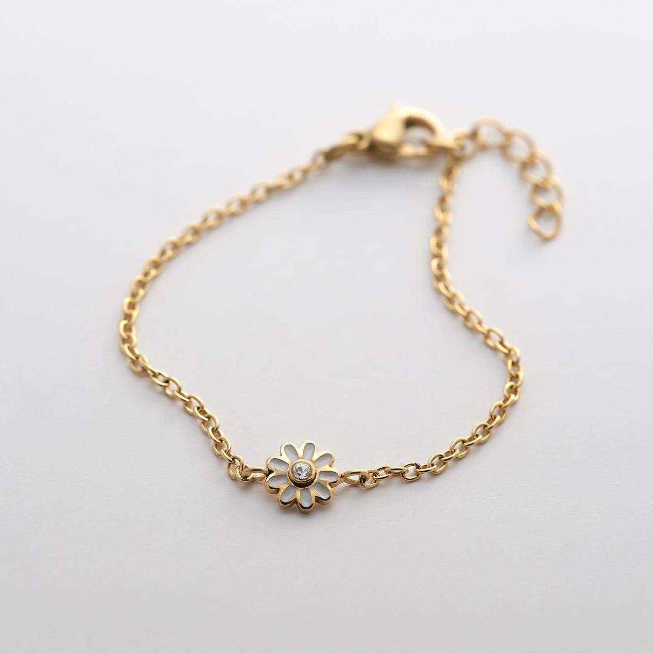 Bracelet FAVS Little Friends en acier inoxydable plaqué or avec une fleur en émail blanc, ornée d'une zircone.