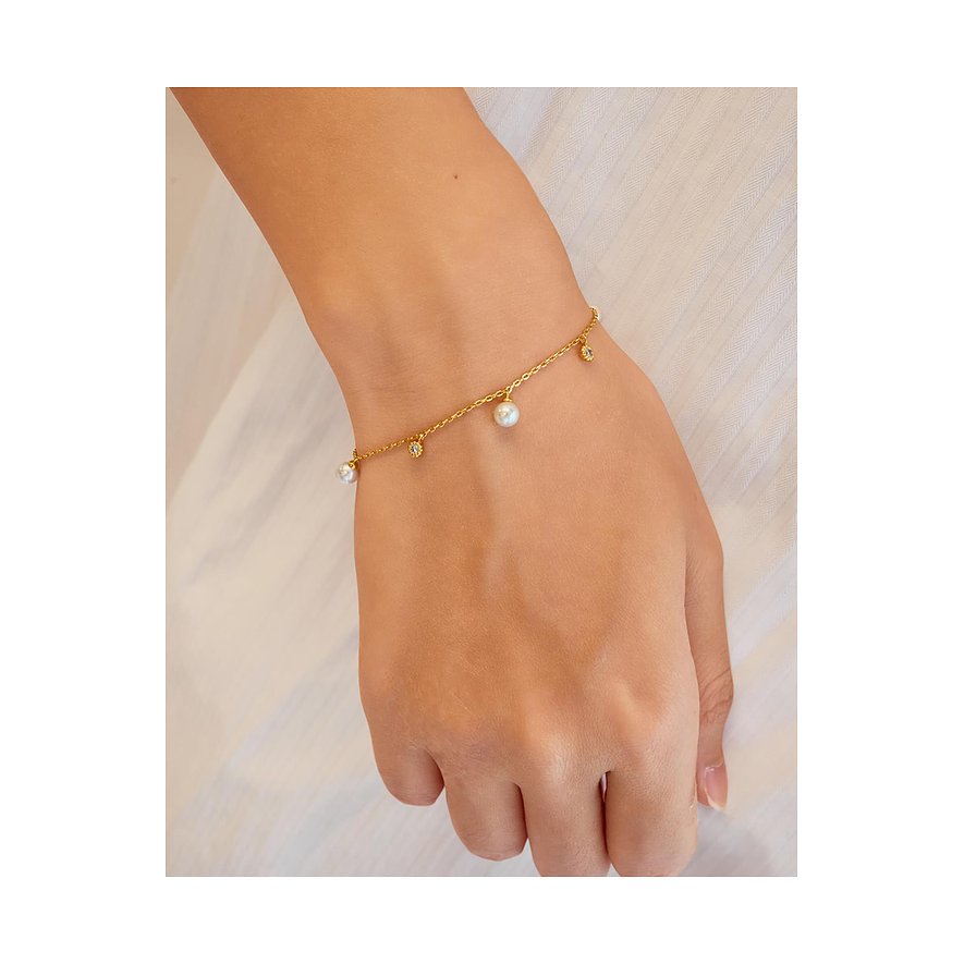 Ania Haie Armband aus vergoldetem Silber mit Zirkonia- und Perlenanhängern am Handgelenk getragen.