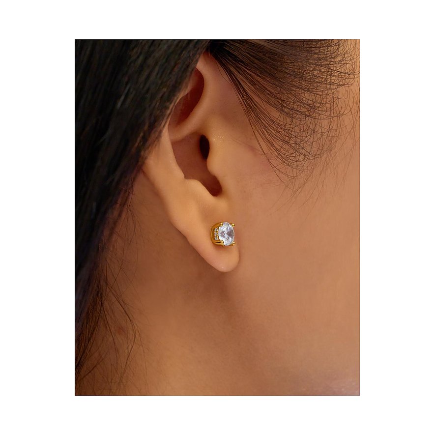 Ein Ania Haie Ohrstecker aus vergoldetem Silber mit rundem Zirkonia, getragen am Ohr eines Models.