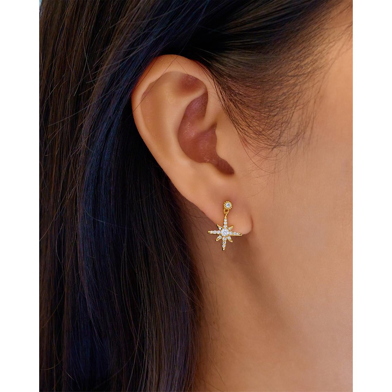 Un bijou d'oreille Ania Haie en argent avec des pierres de zircone en forme d'étoile, porté à une oreille.