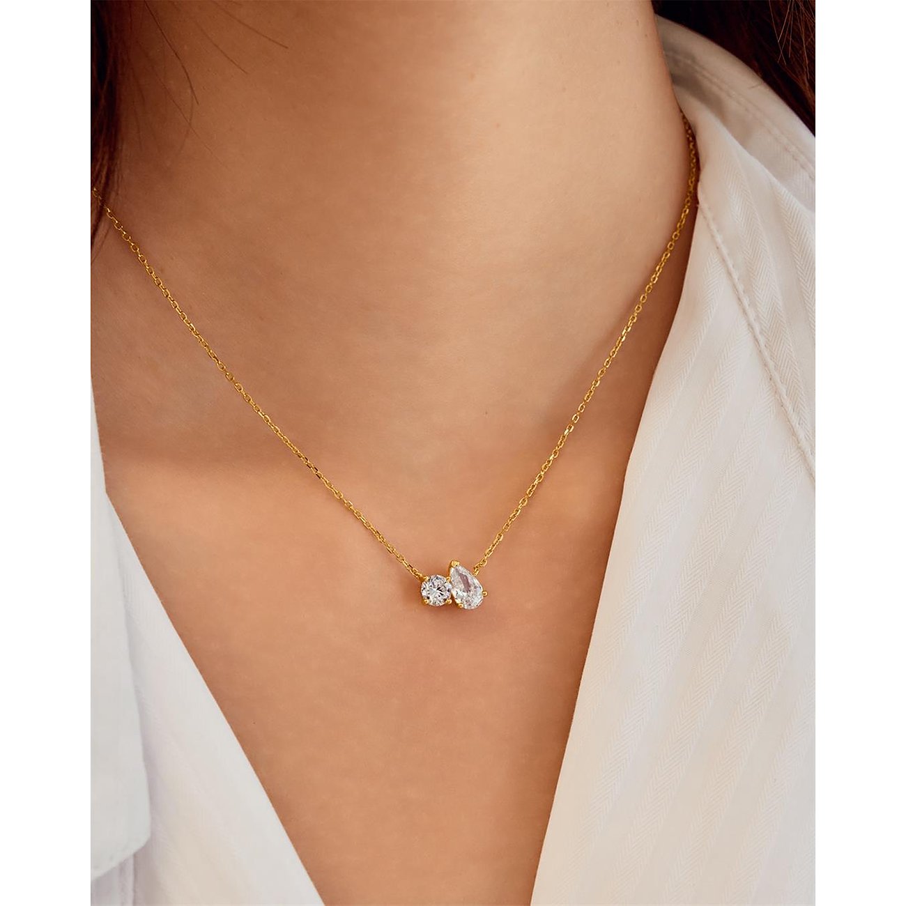 Collier Ania Haie en argent plaqué or, avec deux pendentifs zircones serrés, porté autour d'un cou.