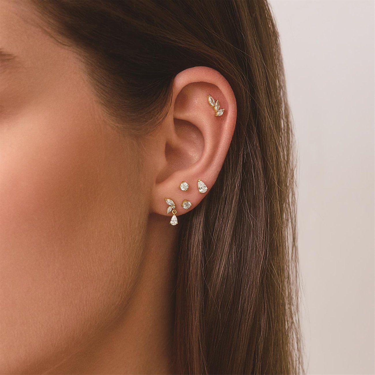 Vrouw draagt Ania Haie zilveren sieraden: bladvormige piercing en oorstekers met zirkonia-druppels.
