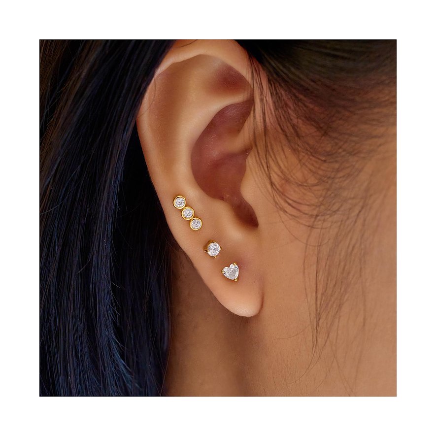 Ein Ohr mit Ania Haie Ohrschmuck aus vergoldetem Silber mit Zirkonia-Farbsteinen: Drei runde und ein Herzohrstecker.