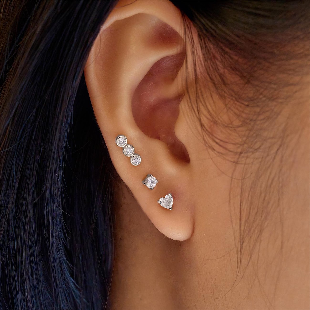 Am Ohr getragenes Ania Haie Ohrschmuck Set aus Silber mit Zirkonia, bestehend aus drei runden und einem herzförmigen Ohrring.