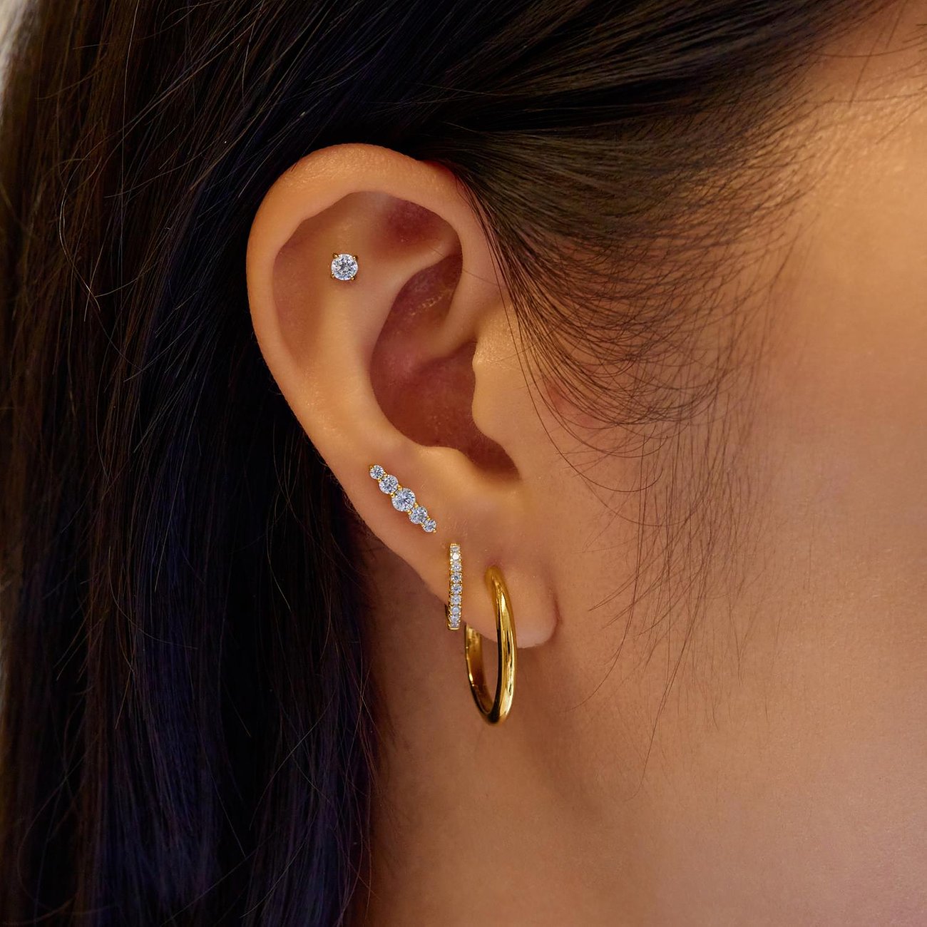 Am Ohr getragenes Ania Haie Ear Cuff aus vergoldetem Silber mit drei Zirkonia als Farbstern.