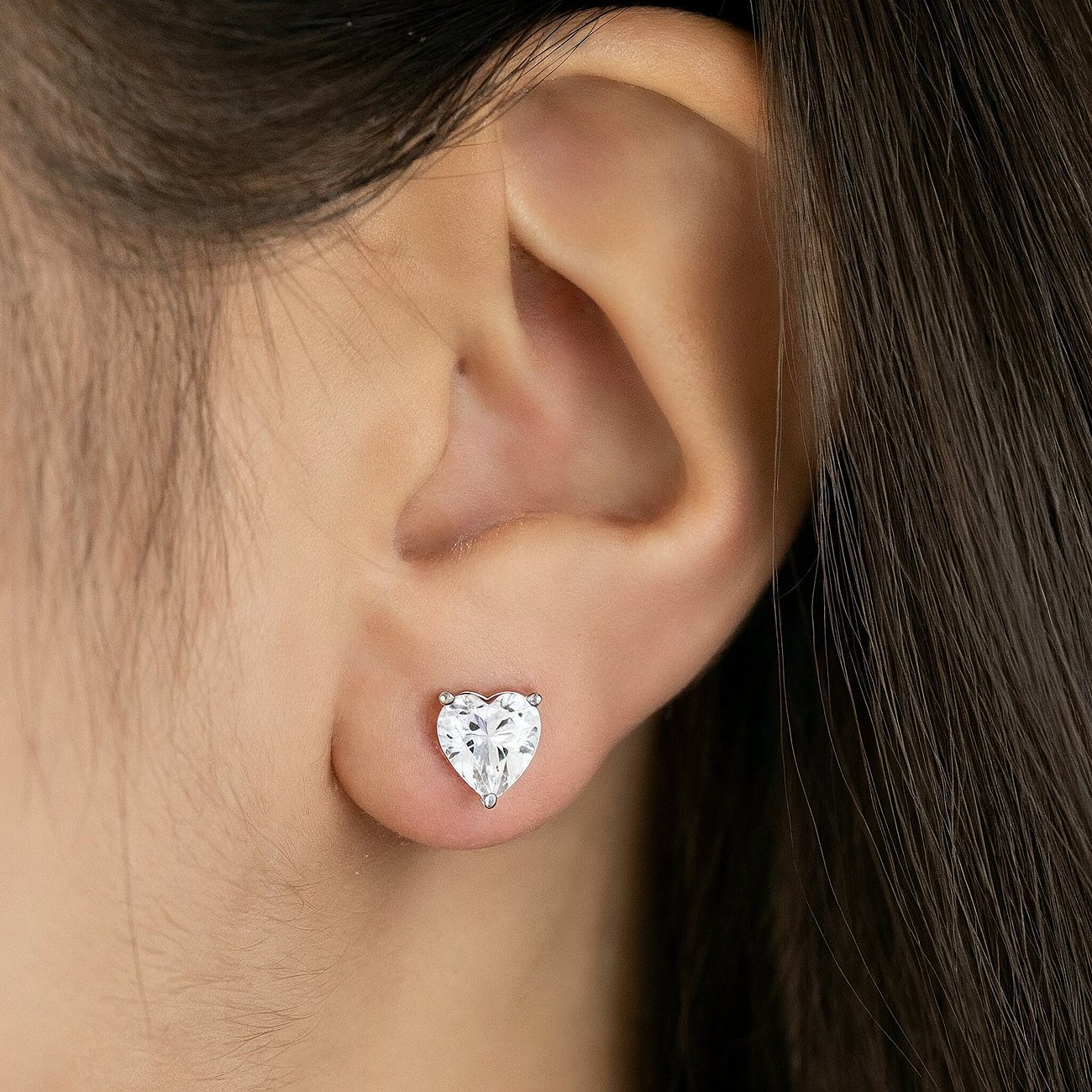 Ein Engelsrufer Herz-Ohrstecker aus 925er Silber mit Zirkonia, getragen am Ohr. Der Farbstein ist in Herzform geschliffen.