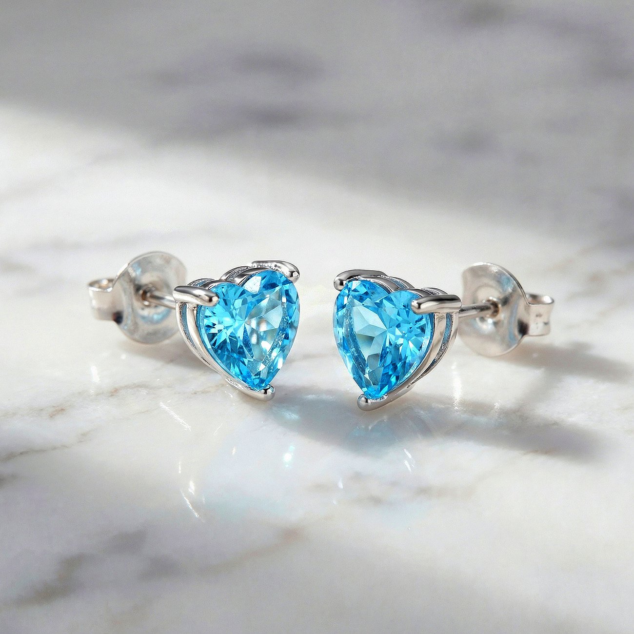 Engelsrufer Ohrstecker aus 925er Silber mit herzförmigen, hellblauen Zirkonia Farbsteinen.