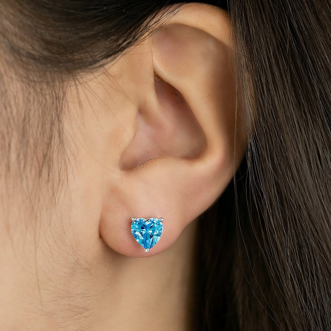 Engelsrufer Ohrstecker aus 925er Silber mit herzförmigem, türkisfarbenem Zirkonia, getragen am Ohr einer Frau.