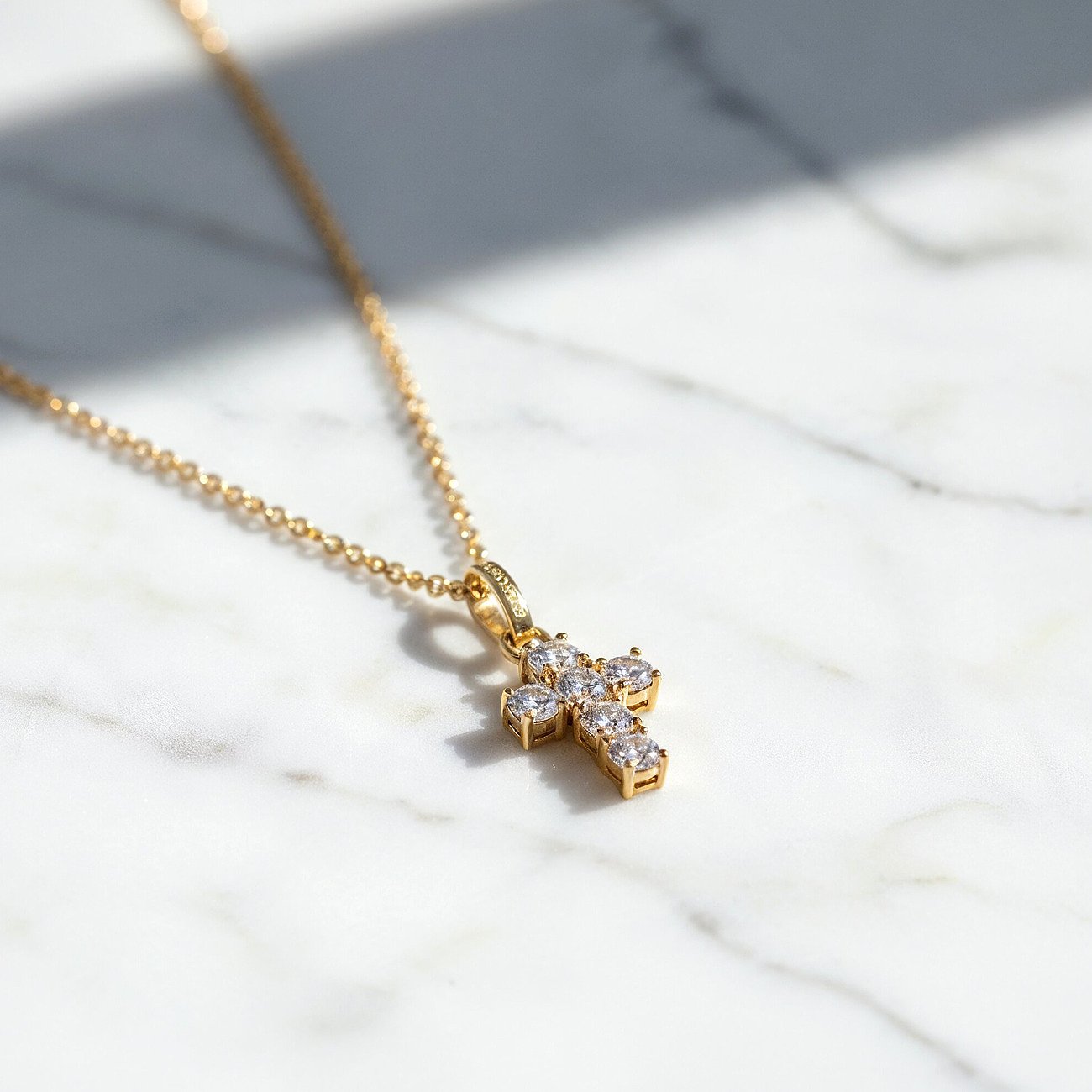 Engelsrufer Halskette aus vergoldetem Silber mit Zirkonia-Kreuzanhänger, schräg von oben aufgenommen.