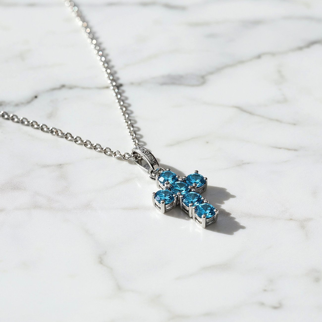 Engelsrufer Kreuzanhänger aus Silber mit blauen Zirkonia Farbsteinen an einer filigranen Halskette.