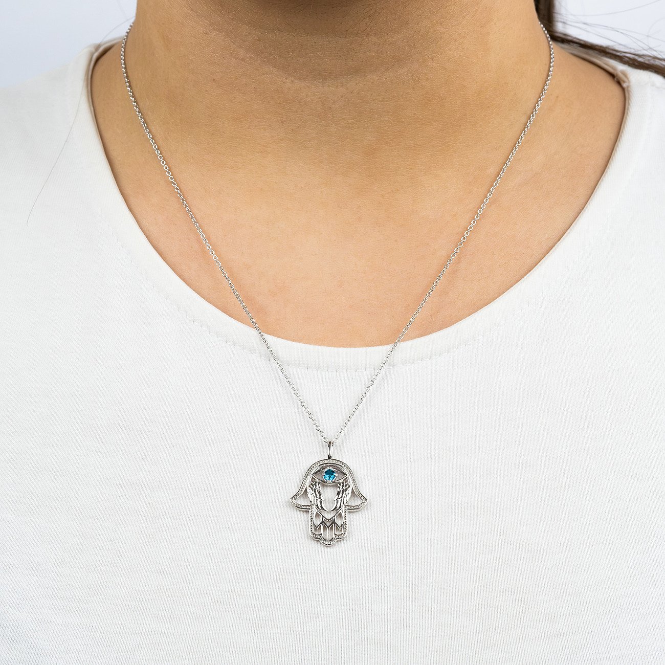 Engelsrufer Halskette aus 925er Silber mit Hamsa-Anhänger und blauem Zirkonia Farbsteln am Hals getragen.