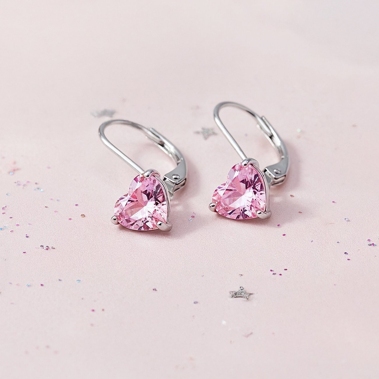 Engelsrufer Ohrschmuck aus Edelstahl mit herzförmigen rosa Zirkonia Farbsteinen, leicht schräg von oben aufgenommen.