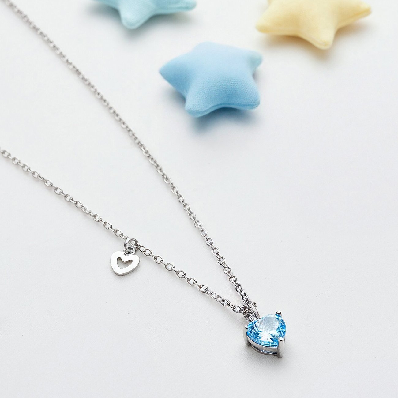 Engelsrufer halsband i rostfritt stål med ljusblå hjärtformad zirkoniasten och litet hjärthänge.