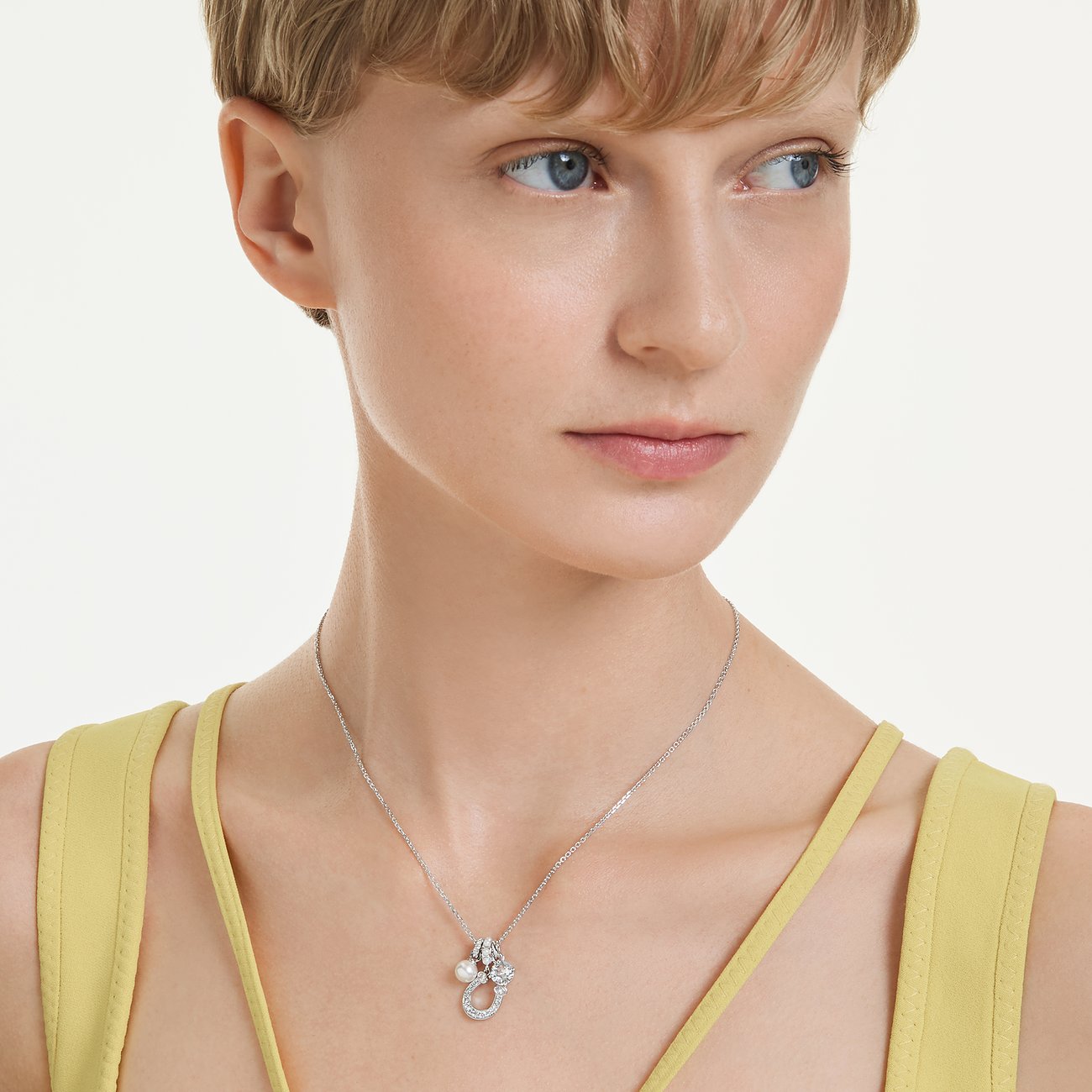 Eine Frau trägt eine Swarovski Halskette aus Metall mit Anhänger, verziert mit einem Farbstein und einem Swarovski-Kristall.