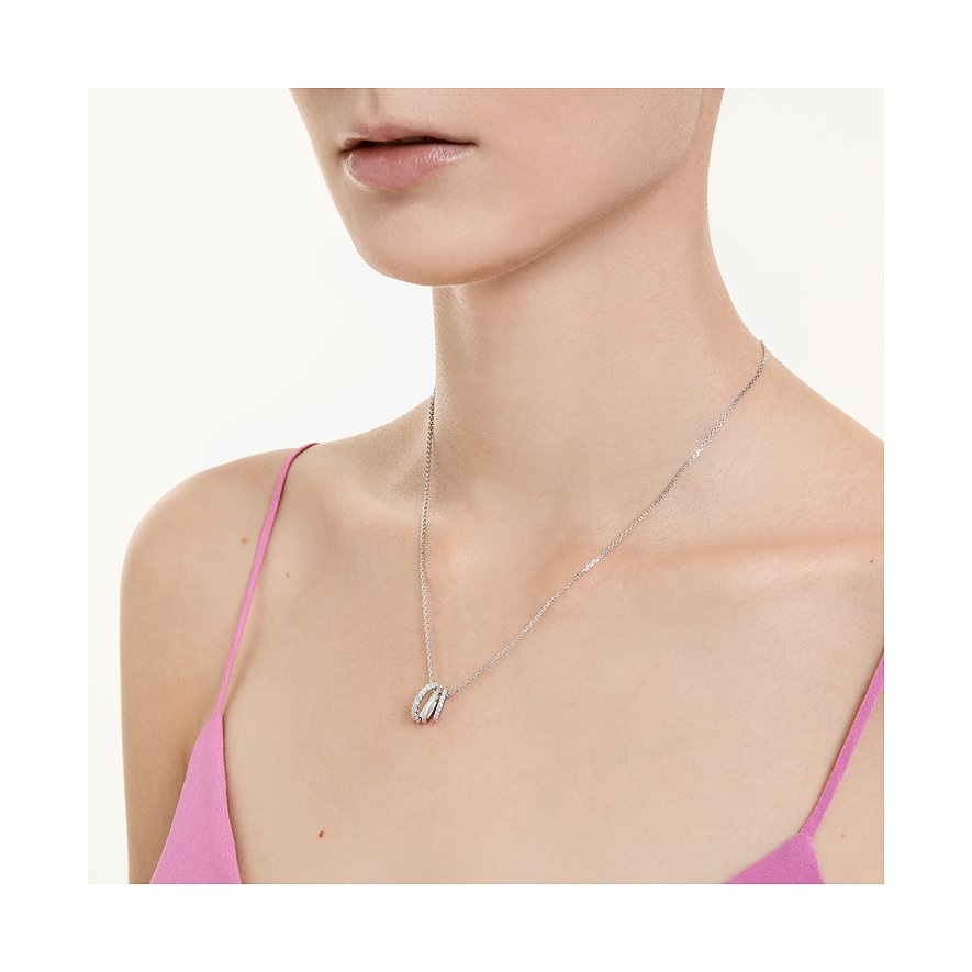 Nahaufnahme: Swarovski Metall-Halsschmuck, drei ineinandergreifende Ringe, klare Edelsteine, an einem Model.