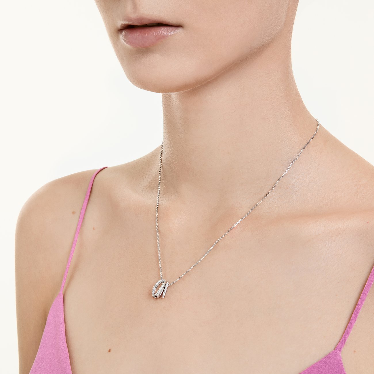 Nahaufnahme: Swarovski Metall-Halsschmuck, drei ineinandergreifende Ringe, klare Edelsteine, an einem Model.