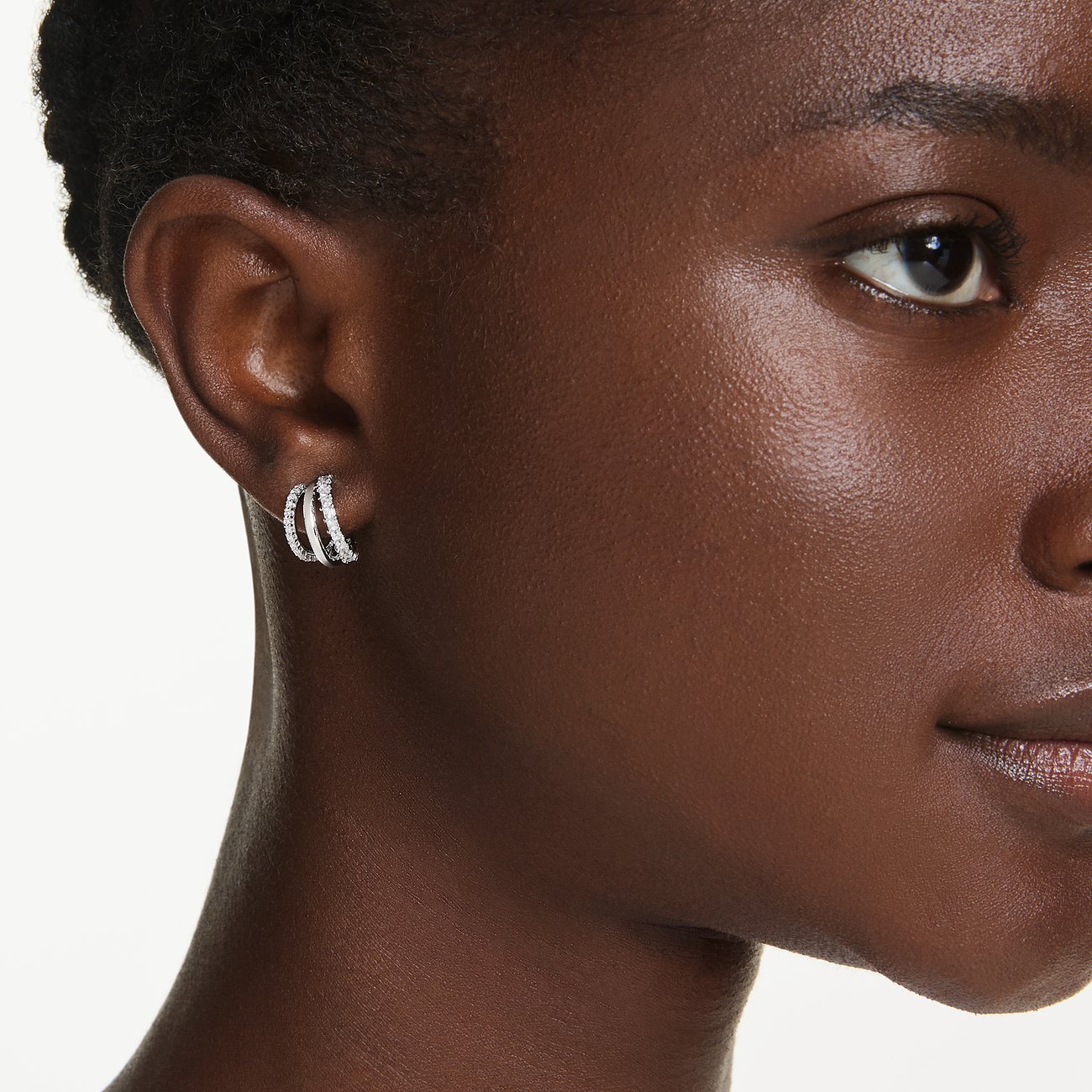 Ein detailreiches Nahaufnahmebild von drei Swarovski Metall-Ohrringen mit funkelnden Farbkristallen.