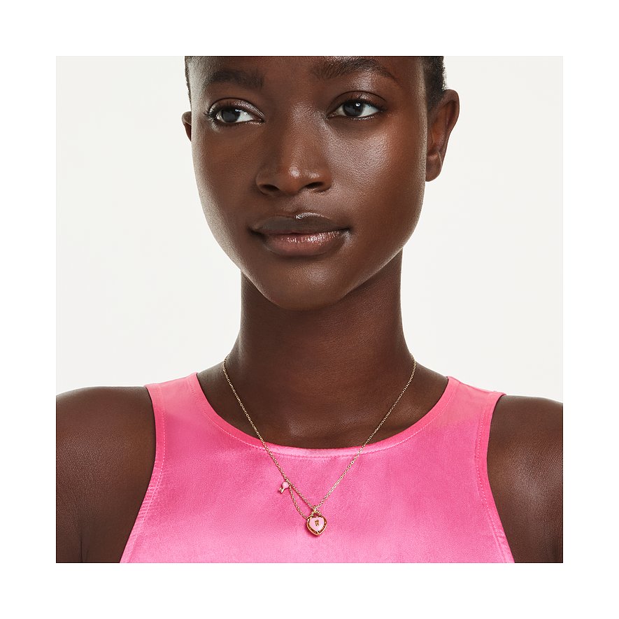 Eine Frau trägt eine Swarovski Halskette aus Metall mit einem rosafarbenen Herz-Anhänger mit Swarovski-Kristall.