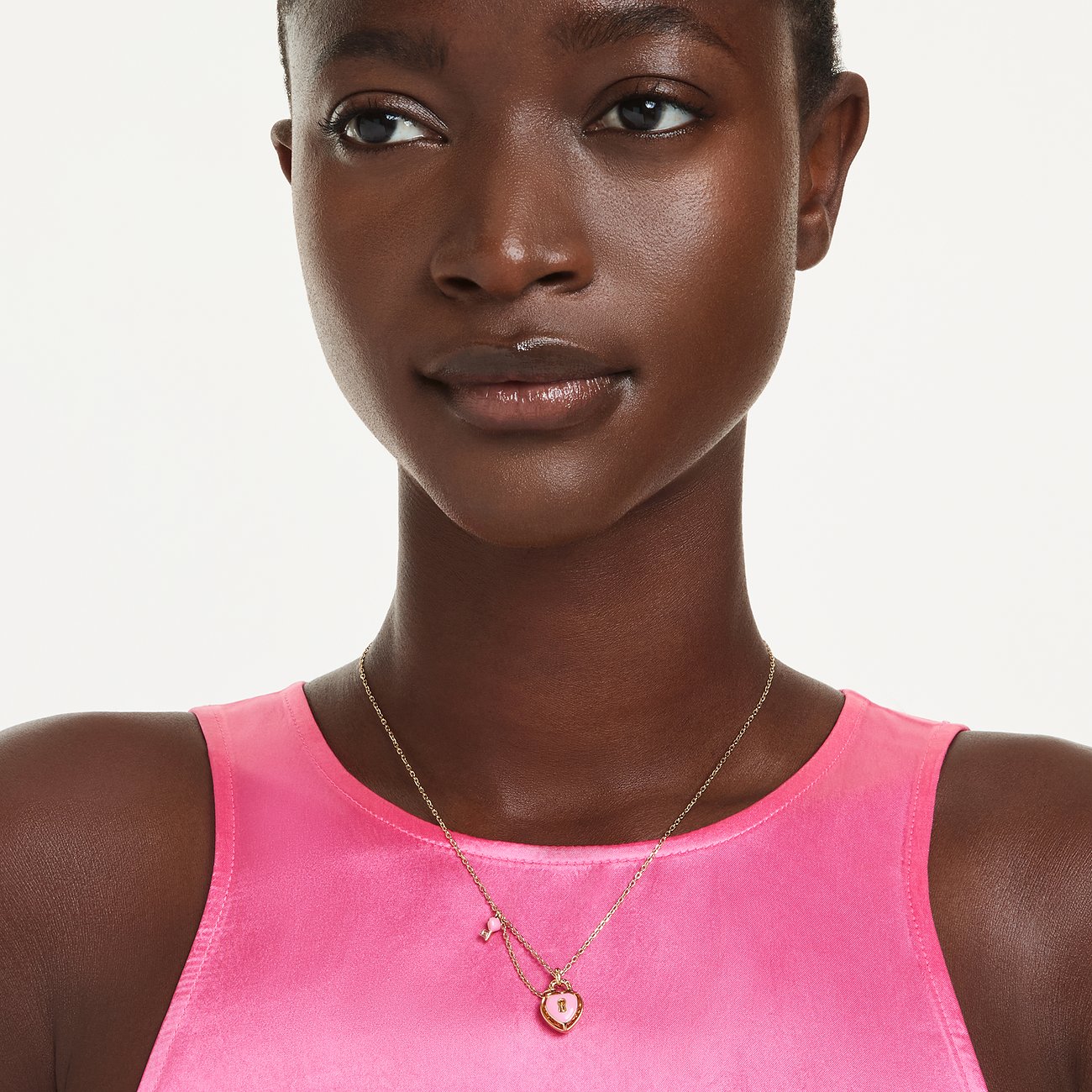 Eine Frau trägt eine Swarovski Halskette aus Metall mit einem rosafarbenen Herz-Anhänger mit Swarovski-Kristall.