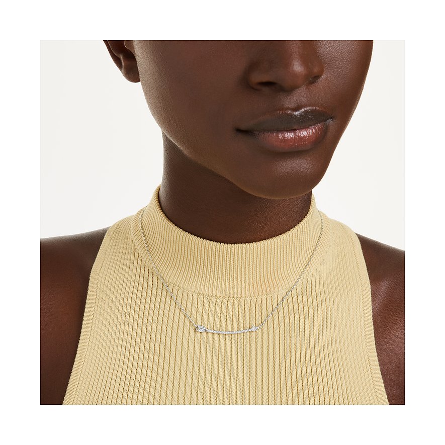 Nahaufnahme eines silberfarbenen Swarovski Halschmuckes mit Pfeilmotiv und Kristallen auf dem Dekolleté eines Models.