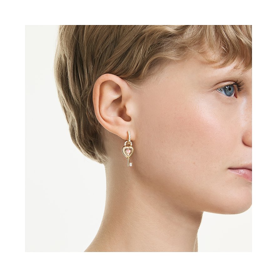 Nahaufnahme eines Swarovski Ohrschmucks in Form eines Schlüssels mit herzförmigem, rosafarbenem Farbstein.