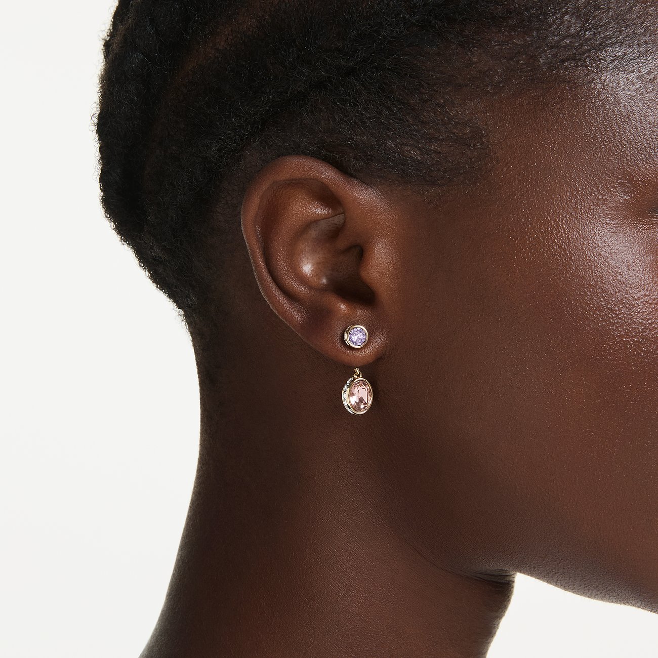 Swarovski oorsieraad van metaal met twee geslepen Swarovski kristallen. De bovenste is paars, de onderste roze.