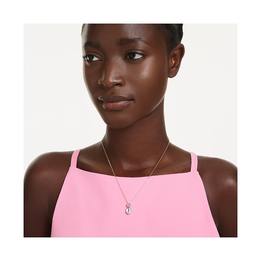 Ein Model trägt eine Goldkette mit einem länglichen Anhänger in rosa und hellblauem Swarovski-Kristall.