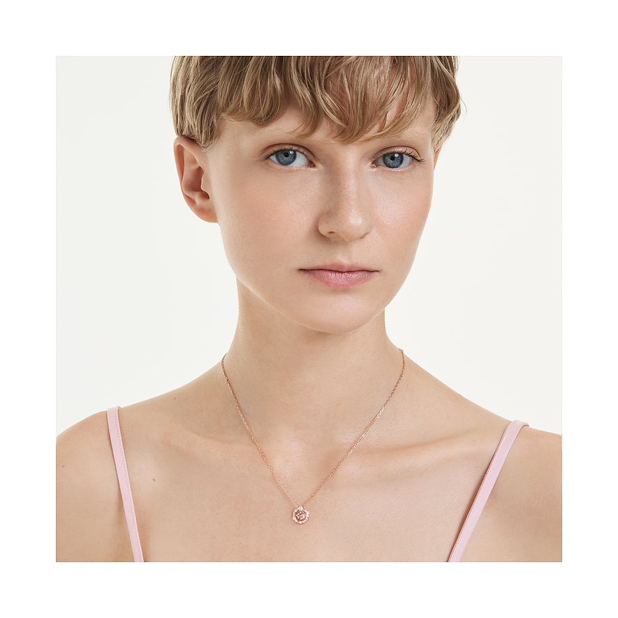 Model trägt eine Swarovski Halskette aus roségoldfarbenem Metall mit einem kleinen, runden Anhänger mit Farbedelsteinen.