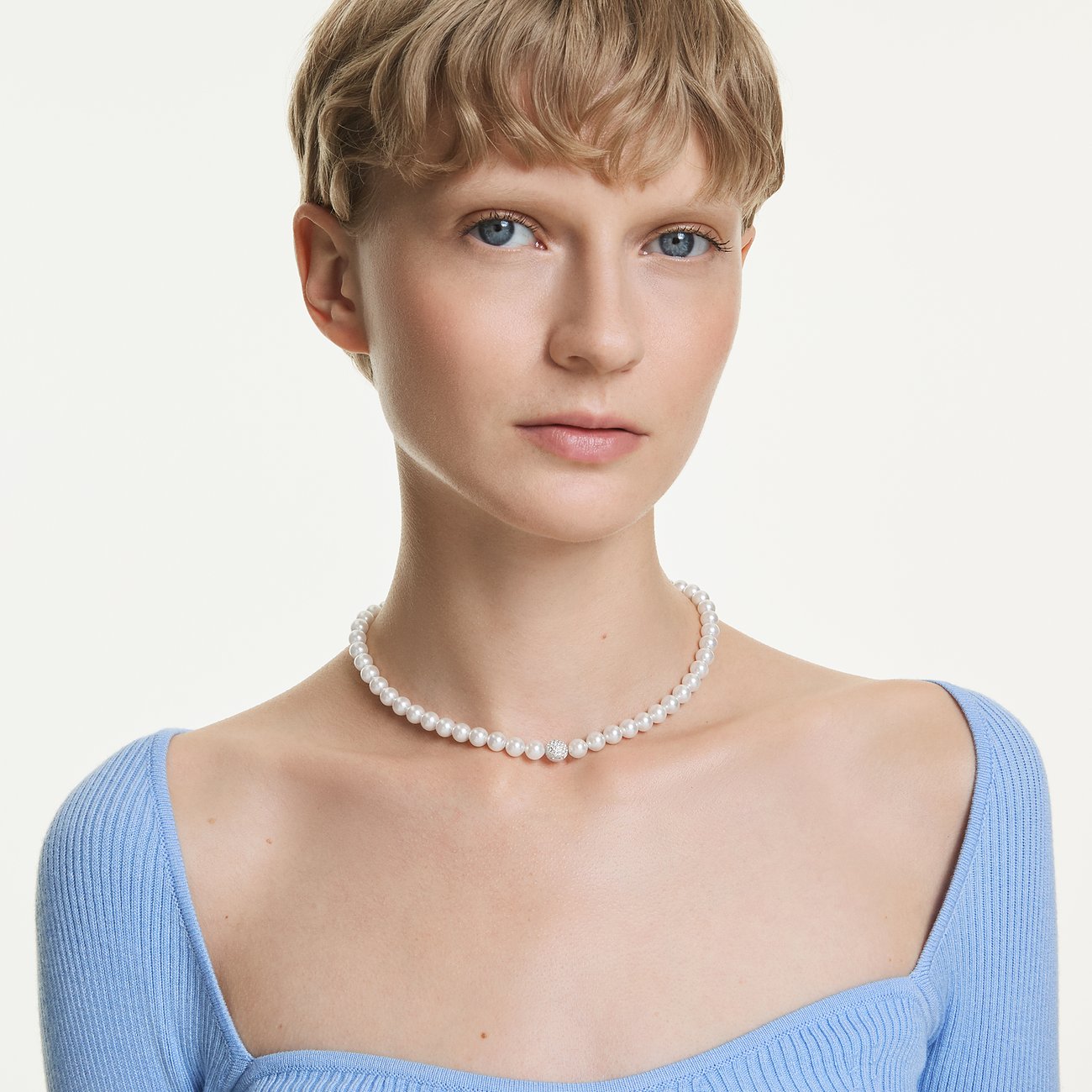 Model draagt een Swarovski ketting met kleine parels en een sprankelende Swarovski kristal in het midden.