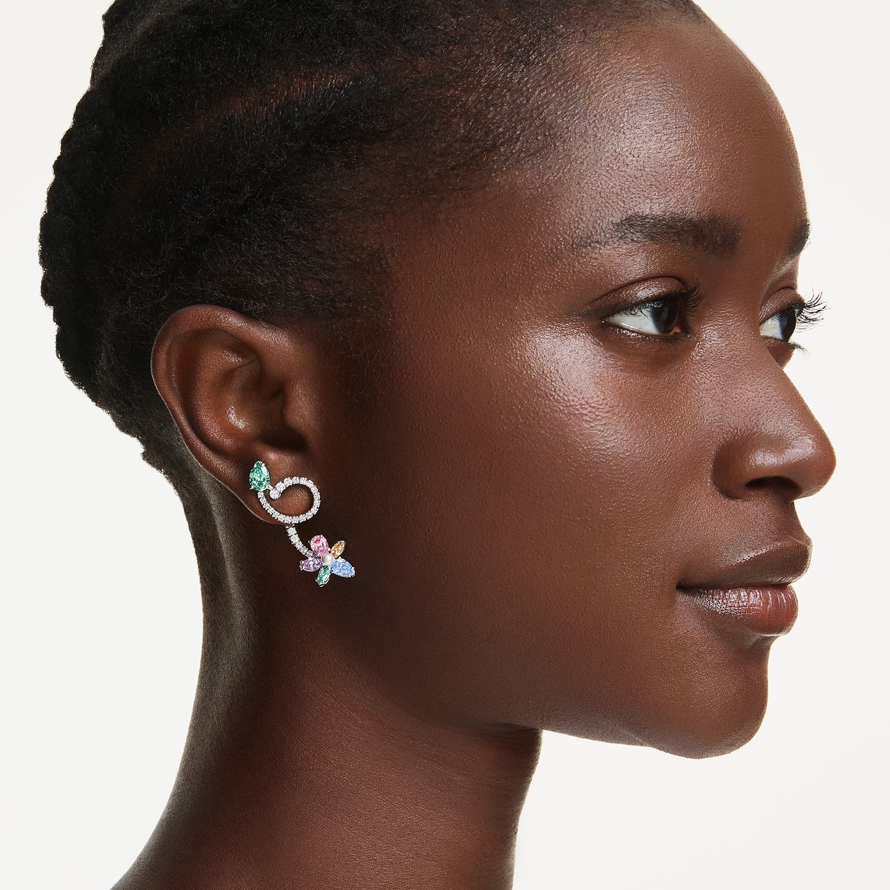 Ein Swarovski Ranken-Ohrschmuck aus Metall mit bunten Swarovski-Kristallen ziert das Ohr eines Models.