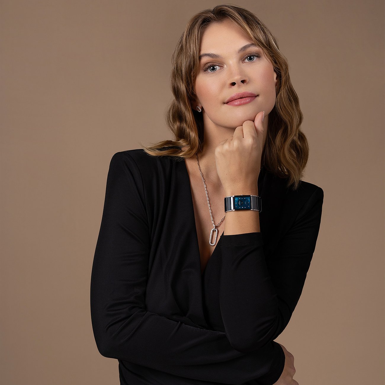 Ein Model trägt eine rechteckige Jacques Lemans Damenuhr aus Edelstahl mit blauem Zifferblatt am Handgelenk.