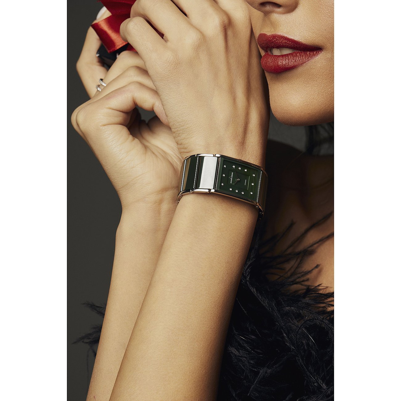 Nahaufnahme einer Jacques Lemans Damenuhr aus Edelstahl mit rechteckigem grünen Zifferblatt am Handgelenk einer Frau.