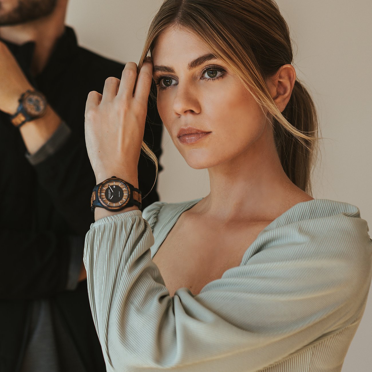 Close-up van een vrouw die een donkerbruin roestvrijstalen Jacques Lemans herenhorloge draagt.
