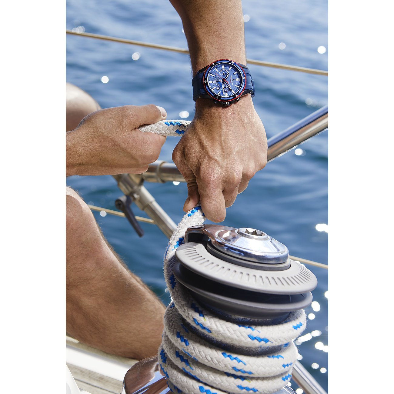 Jacques Lemans herrklocka i rostfritt stål på en mans arm, som håller ett rep på en båt med havet i bakgrunden.