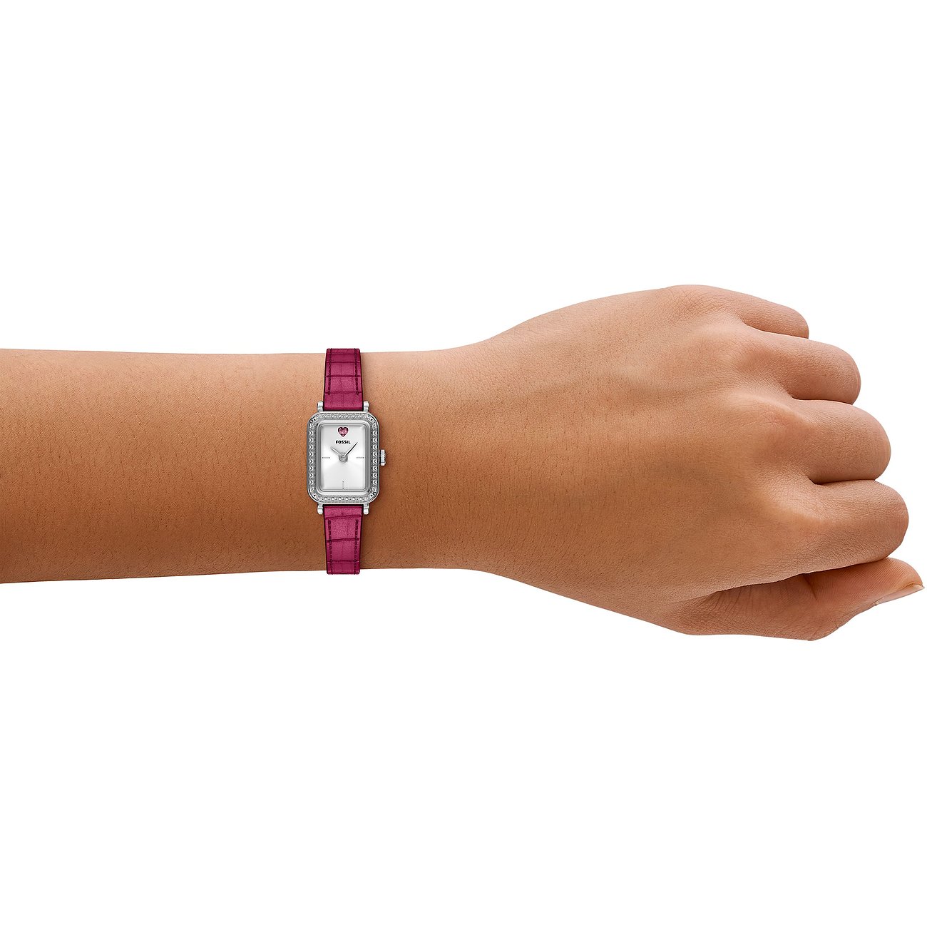 Eine Fossil Damenuhr aus Edelstahl mit rechteckigem Zifferblatt und fuchsiafarbenem Armband, getragen an einem Handgelenk.