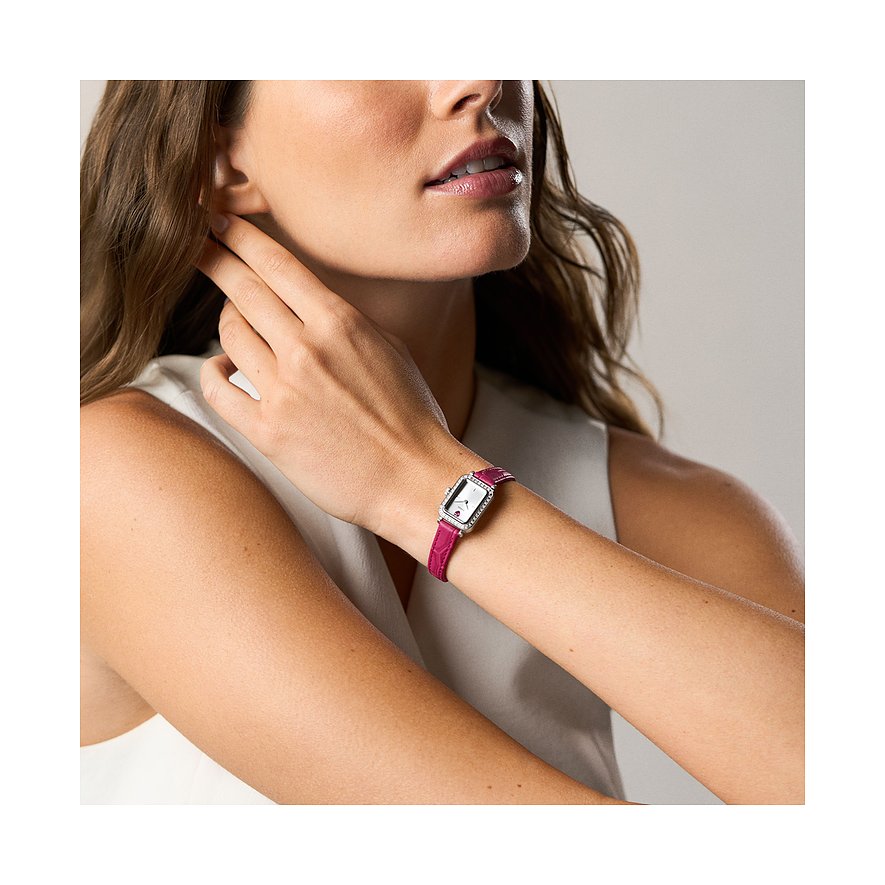 Eine Frau trägt eine rechteckige Fossil Damenuhr aus Edelstahl mit glänzendem Band und einem fuchsiafarbenen Armband.