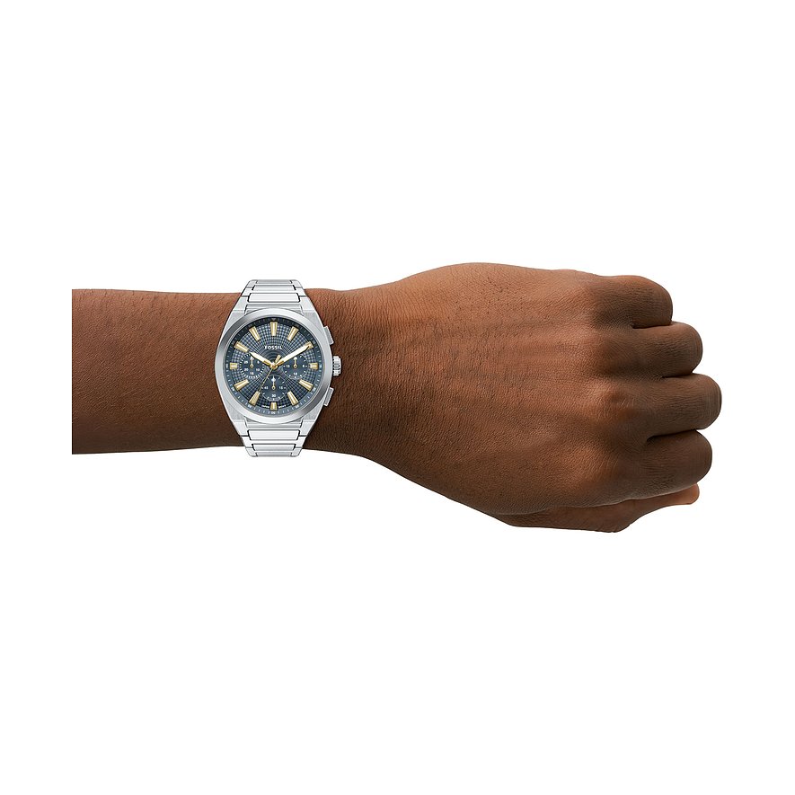Fossil Herrenuhr aus silberfarbenem Edelstahl mit dunkelblauem Zifferblatt und goldenen Akzenten am Handgelenk eines Mannes.
