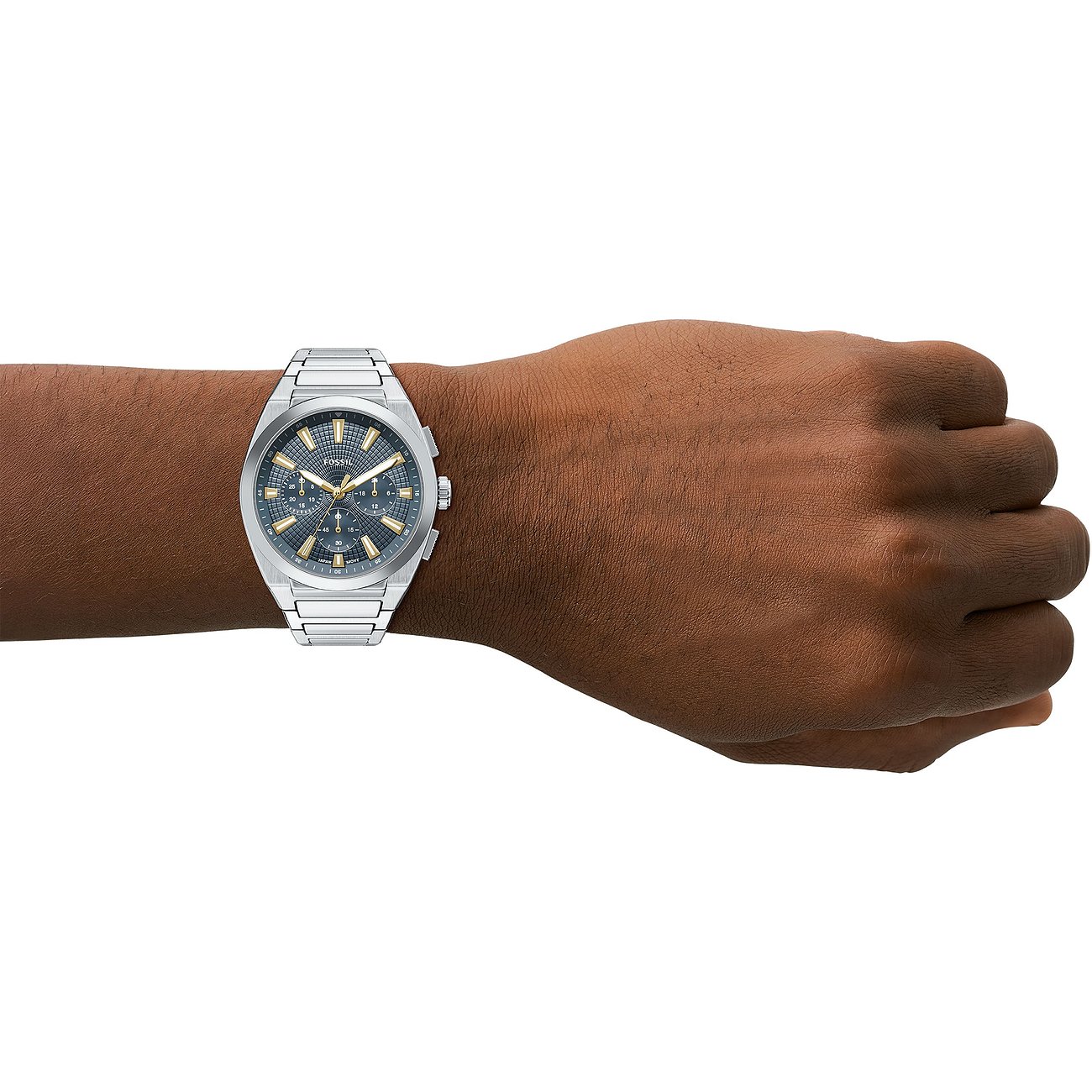 Fossil Herrenuhr aus silberfarbenem Edelstahl mit dunkelblauem Zifferblatt und goldenen Akzenten am Handgelenk eines Mannes.