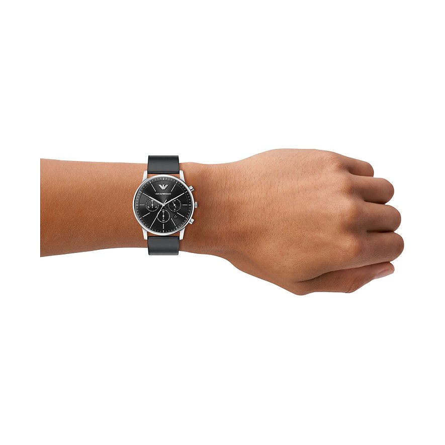 Eine Emporio Armani Herrenuhr aus Edelstahl mit schwarzem Zifferblatt und Lederarmband am Handgelenk getragen.
