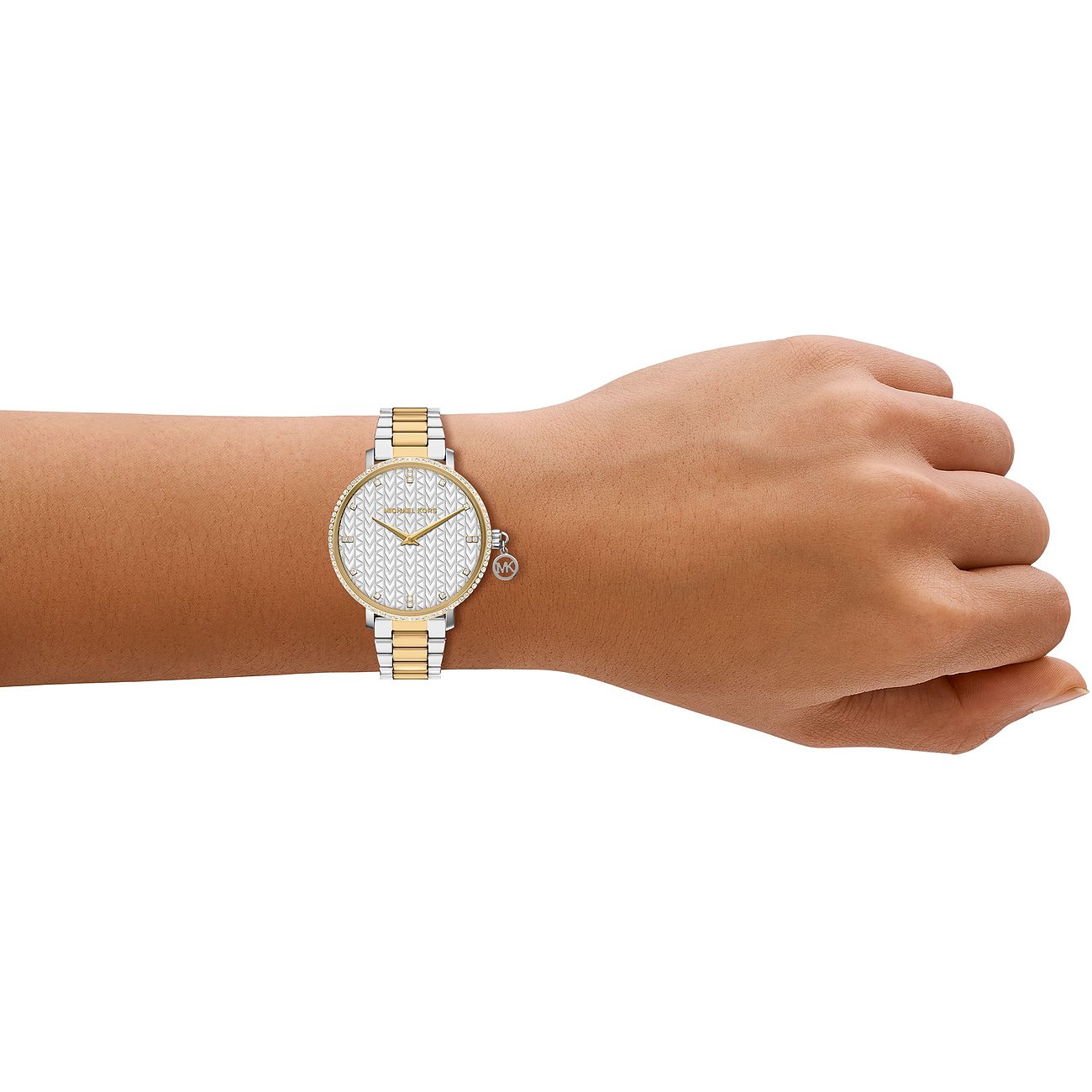 En Michael Kors damklocka i rostfritt stål på handleden, med tvåfärgat guld- och silverfärgat armband.