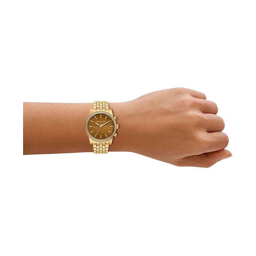 Michael Kors dameur i guldfarvet rustfrit stål med tigerøje urskive og ædelstenskant, båret på håndleddet.