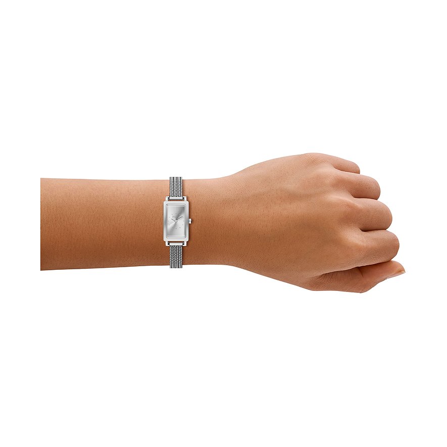 En Skagen damklocka i rostfritt stål med rektangulär urtavla och silverfärgad milaneselänk, buren på handleden.