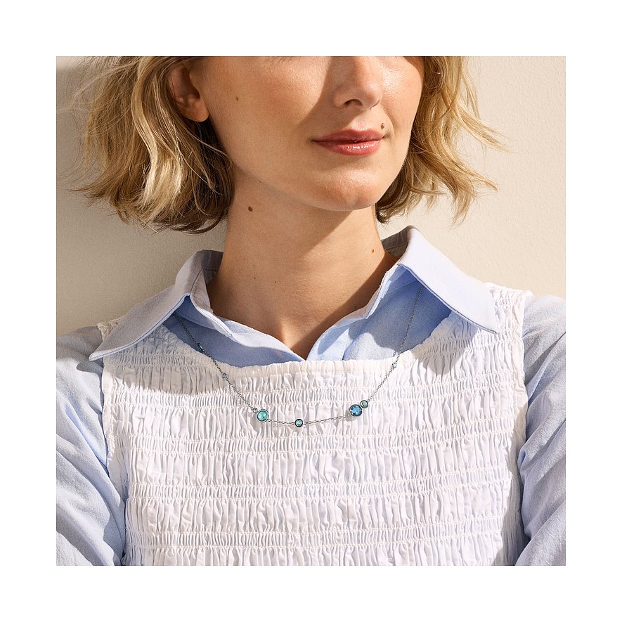 Primo piano di una donna che indossa una collana Skagen in acciaio inossidabile con varie pietre di vetro blu e turchesi.