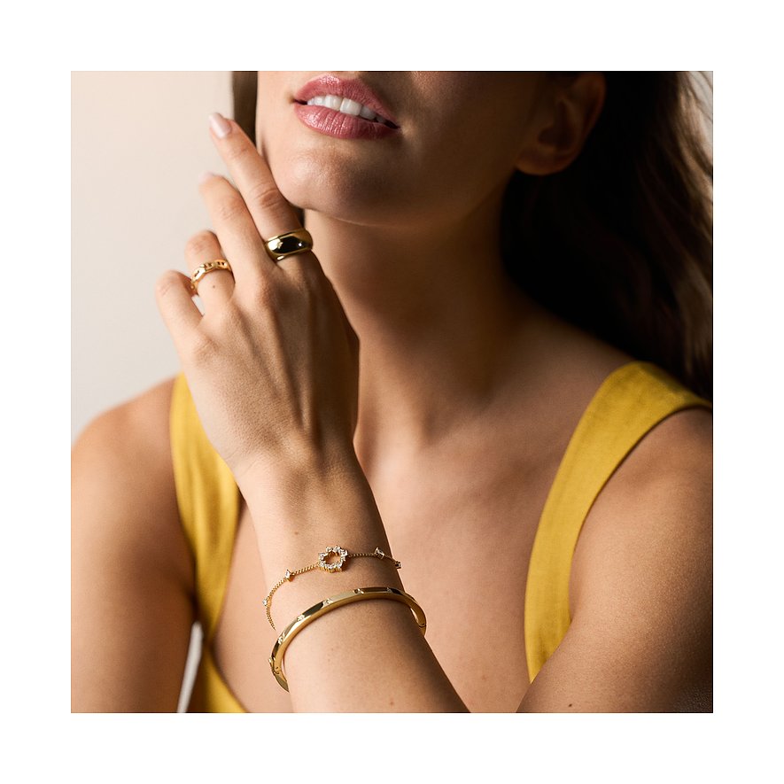 Närbild: elegant kvinna med två Fossil-armband och två metallringar med färgade stenar.