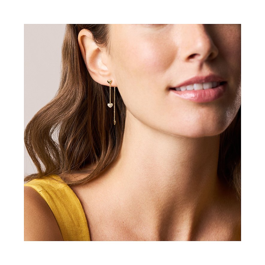 Ein Fossil Ohrschmuck aus Metall im Makrobereich an einer Frau. Der Ohrring hat ein Herz am Ohrläppchen.