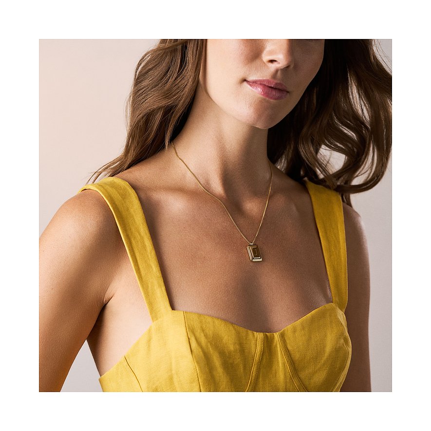 Gros plan : femme portant un collier Fossil en acier inoxydable doré avec un pendentif rectangulaire. Superbe.